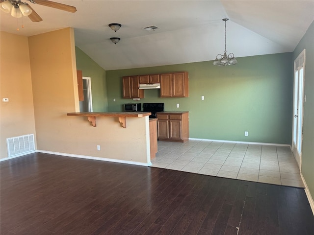 kitchen featuring a kitchen breakfast bar, vaulted ceiling, light hardwood / wood-style flooring, and kitchen peninsula