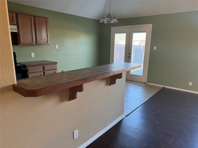 kitchen featuring a breakfast bar, kitchen peninsula, hanging light fixtures, light hardwood / wood-style flooring, and black electric range oven