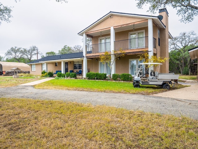 view of front facade featuring a front yard and a balcony