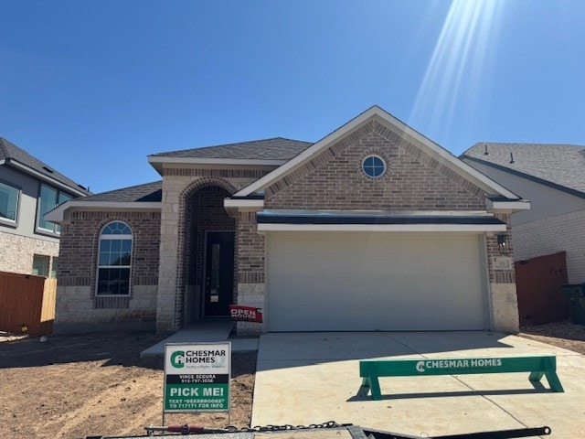 view of front of house with brick siding, stone siding, an attached garage, and driveway