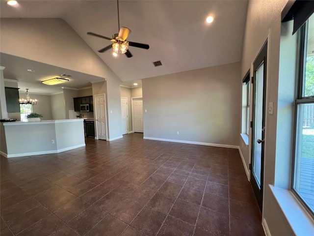 unfurnished living room featuring high vaulted ceiling, dark tile patterned flooring, and ceiling fan with notable chandelier