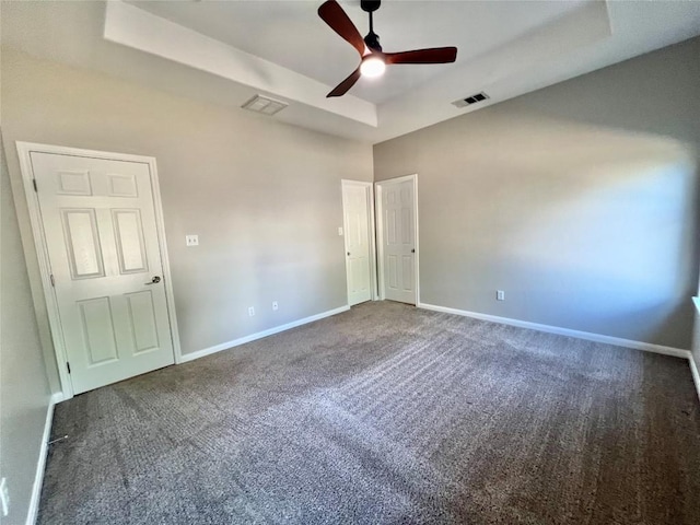 unfurnished bedroom with carpet floors, a tray ceiling, and ceiling fan