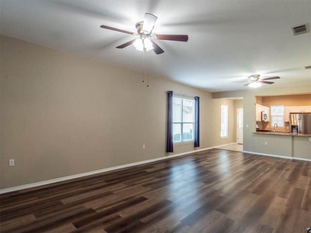 unfurnished living room featuring ceiling fan, sink, and dark hardwood / wood-style floors