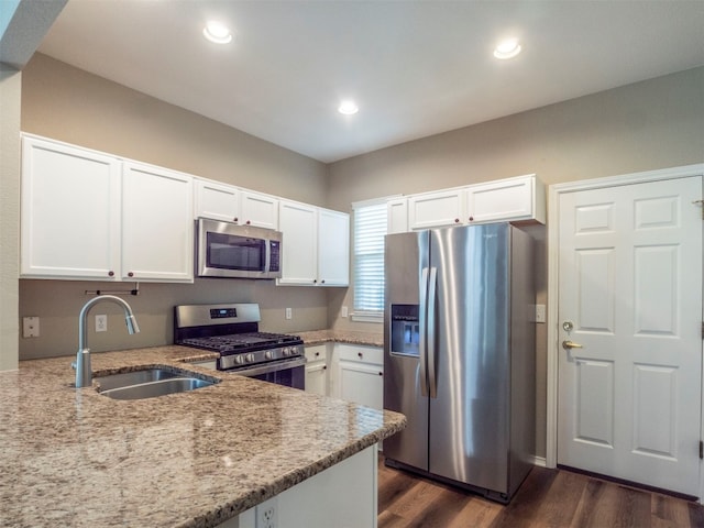 kitchen with light stone counters, appliances with stainless steel finishes, dark hardwood / wood-style flooring, sink, and white cabinets