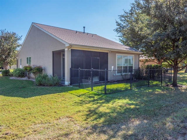 rear view of house featuring a sunroom and a yard