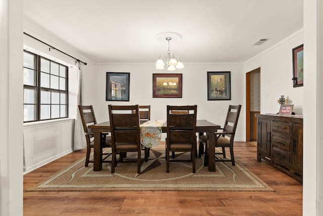 dining room featuring hardwood / wood-style floors, an inviting chandelier, and crown molding