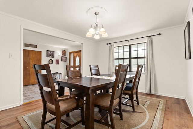 dining area featuring crown molding, hardwood / wood-style flooring, and a chandelier