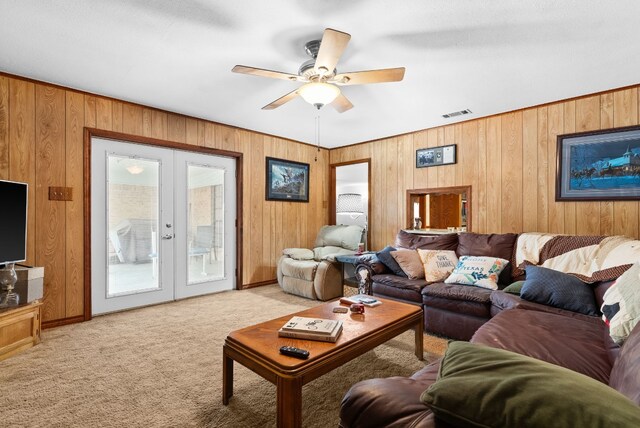 living room featuring french doors, wood walls, and ceiling fan