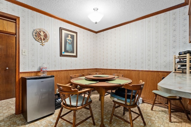 dining space with ornamental molding, wood walls, and a textured ceiling