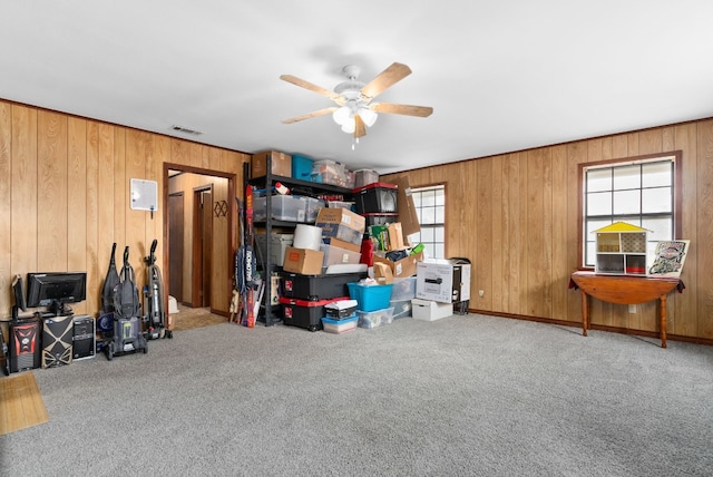 interior space featuring carpet flooring, wood walls, and ceiling fan