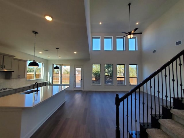 kitchen featuring ceiling fan, sink, tasteful backsplash, cooktop, and an island with sink