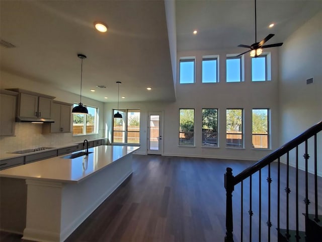 kitchen with backsplash, sink, gray cabinets, black electric cooktop, and a large island