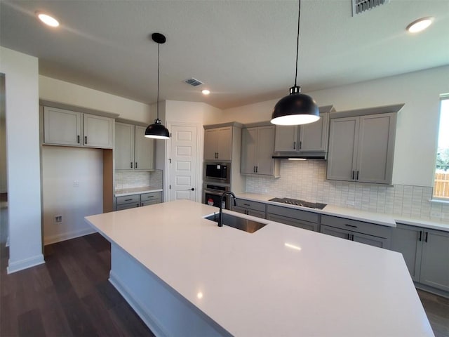 kitchen with tasteful backsplash, gray cabinets, decorative light fixtures, and appliances with stainless steel finishes