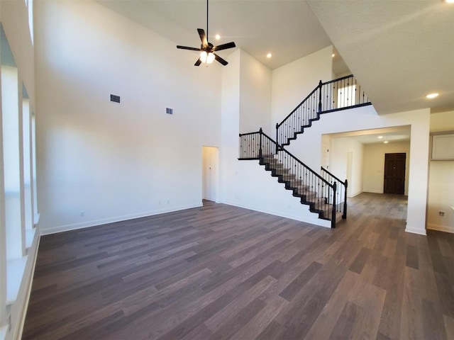 unfurnished living room featuring dark hardwood / wood-style floors, ceiling fan, and a high ceiling