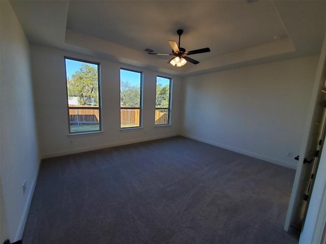 carpeted empty room with ceiling fan and a raised ceiling