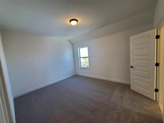 unfurnished room with lofted ceiling and dark colored carpet