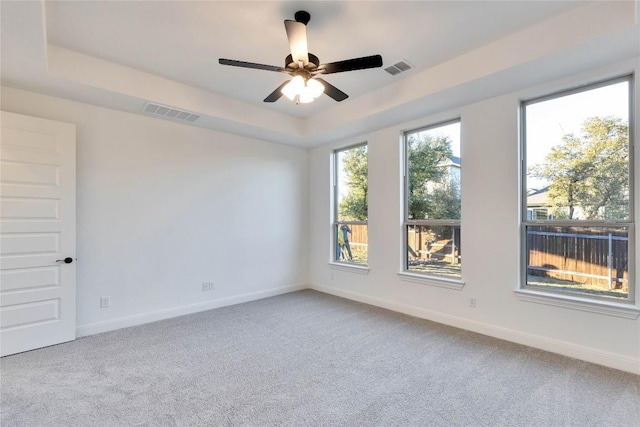 carpeted spare room with a tray ceiling and ceiling fan