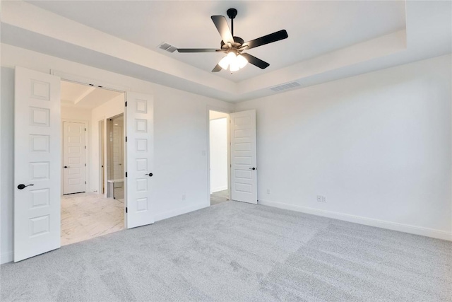 carpeted spare room featuring a raised ceiling and ceiling fan