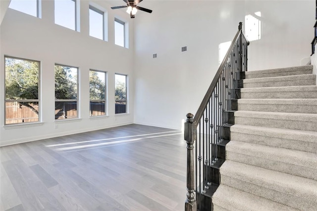 staircase with hardwood / wood-style flooring and ceiling fan