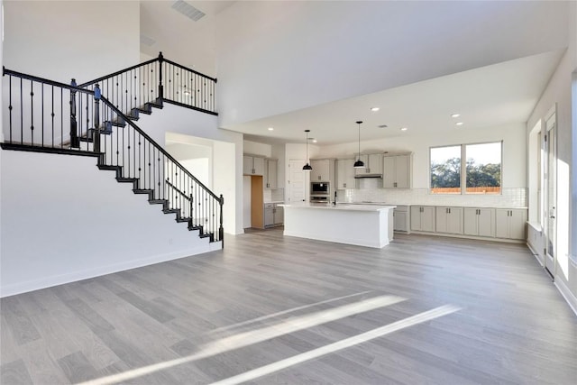 interior space featuring a high ceiling, sink, and light wood-type flooring