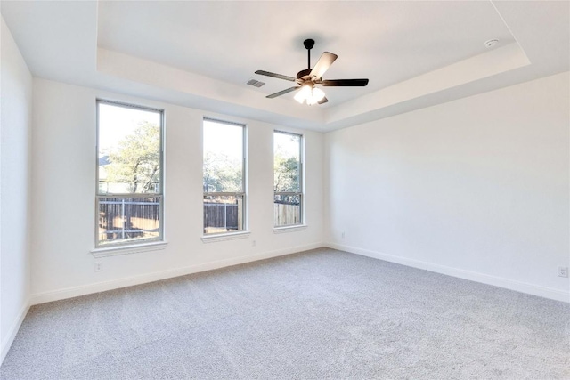 carpeted empty room featuring a raised ceiling and ceiling fan