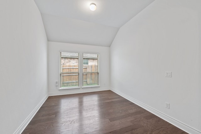 empty room with dark hardwood / wood-style flooring and vaulted ceiling