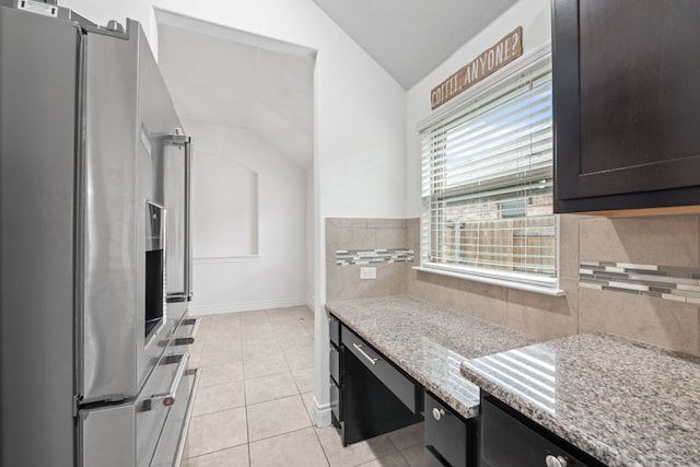 kitchen with light tile patterned flooring, light stone countertops, dark brown cabinets, stainless steel fridge with ice dispenser, and vaulted ceiling