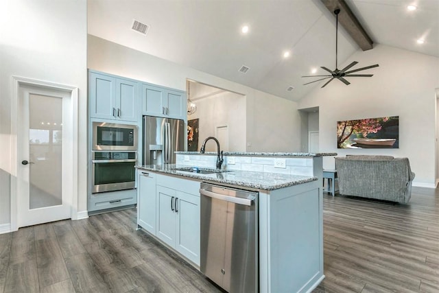 kitchen featuring sink, an island with sink, appliances with stainless steel finishes, beamed ceiling, and dark hardwood / wood-style flooring