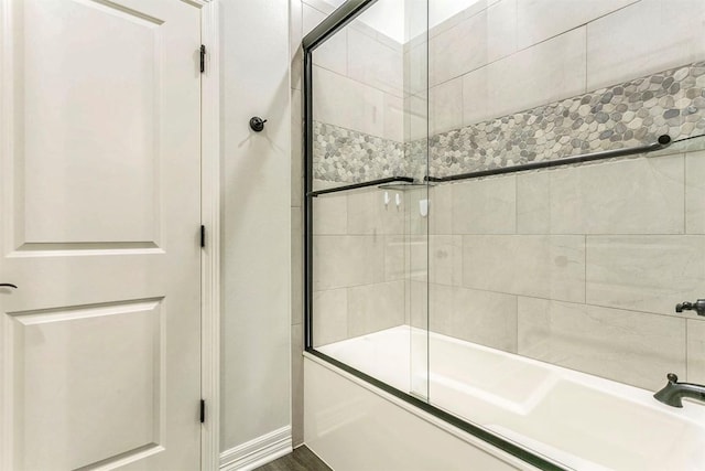 bathroom with hardwood / wood-style floors and combined bath / shower with glass door