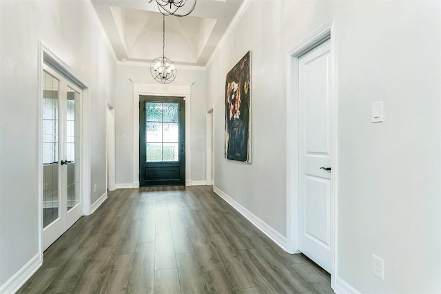 foyer featuring a tray ceiling, dark hardwood / wood-style flooring, french doors, and a chandelier