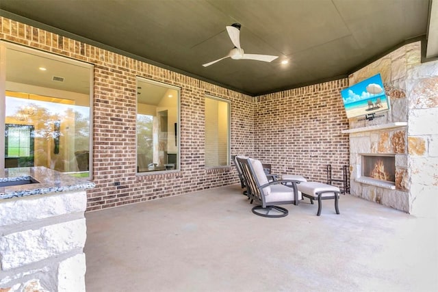 view of patio / terrace featuring ceiling fan and an outdoor stone fireplace