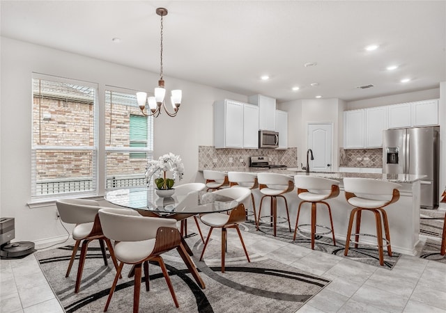 tiled dining room with a wealth of natural light, sink, and an inviting chandelier