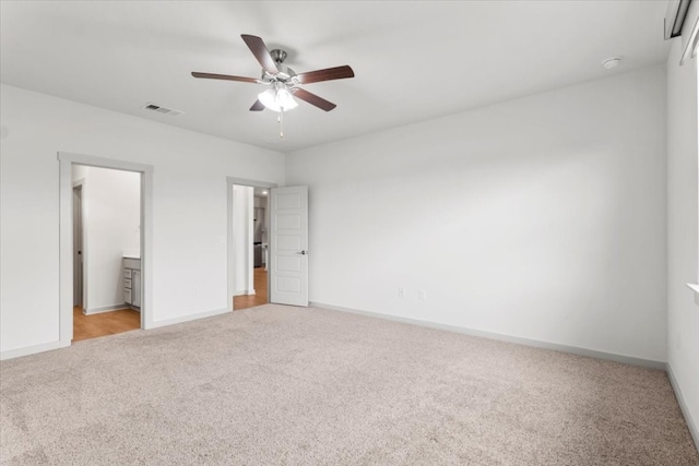 unfurnished bedroom featuring light colored carpet, ceiling fan, and ensuite bath