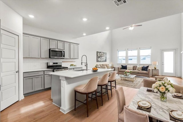13825 Mc Arthur Dr, Manor, TX 78653 - kitchen featuring gray cabinets, appliances with stainless steel finishes, open floor plan, a breakfast bar, and a ceiling fan