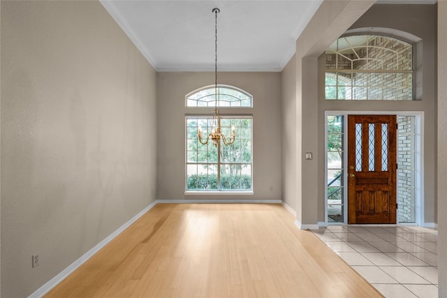 foyer featuring ornamental molding, a towering ceiling, light hardwood / wood-style flooring, and a notable chandelier