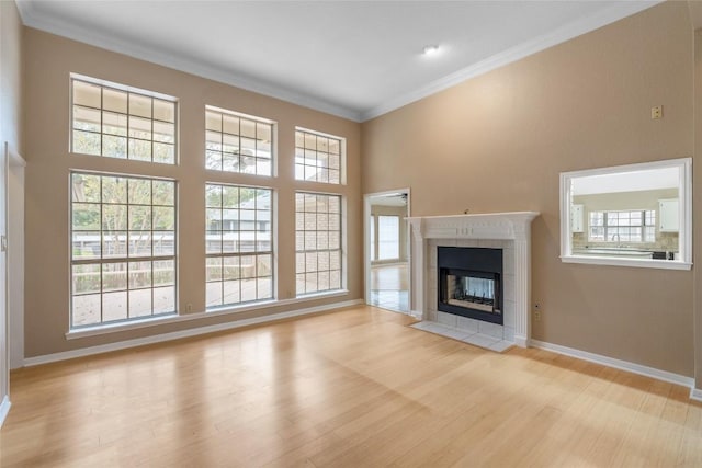 10018 Wild Dunes Dr, Austin, TX 78747 - unfurnished living room featuring light wood-type flooring, crown molding, a tile fireplace, plenty of natural light, and a high ceiling