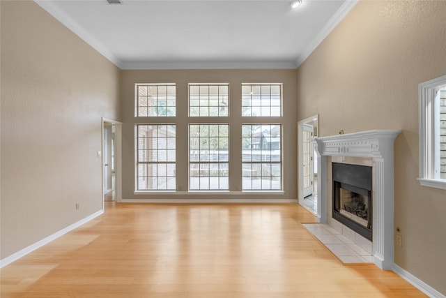 unfurnished living room featuring a tile fireplace, light wood-type flooring, and crown molding