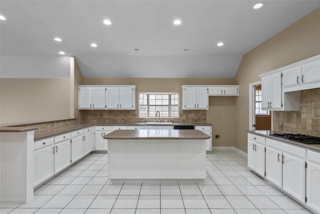 kitchen featuring white cabinets, lofted ceiling, black gas cooktop, and a center island