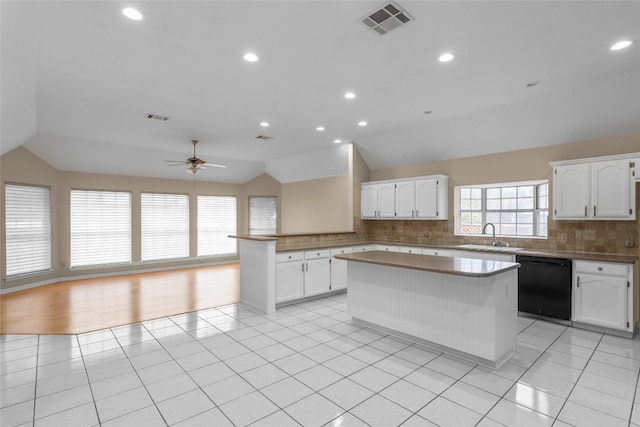 kitchen featuring black dishwasher, white cabinets, and vaulted ceiling