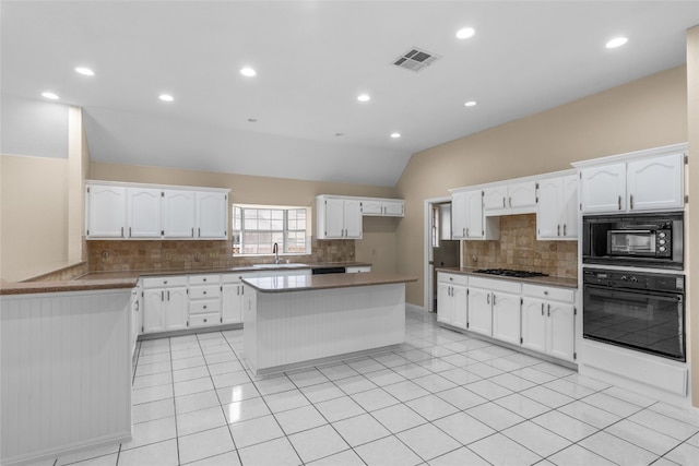 kitchen with white cabinets, black appliances, and vaulted ceiling