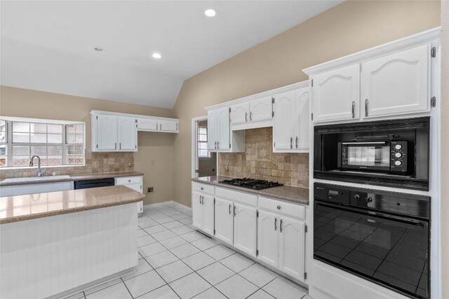 10018 Wild Dunes Dr, Austin, TX 78747 - kitchen with black appliances, vaulted ceiling, white cabinetry, tasteful backsplash, and light tile patterned flooring