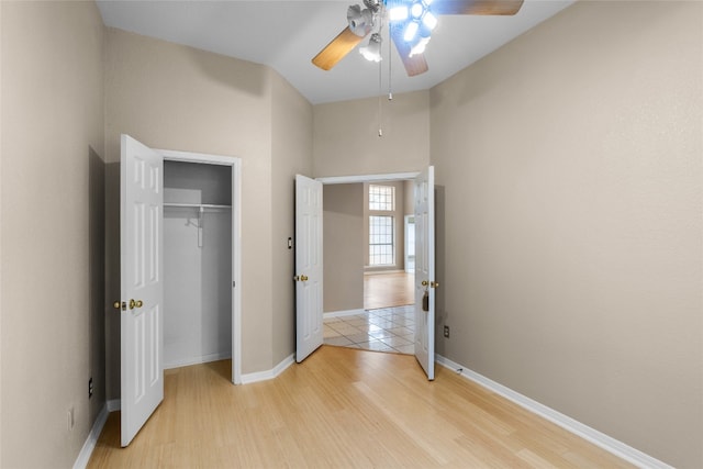 unfurnished bedroom featuring ceiling fan, a closet, and light wood-type flooring