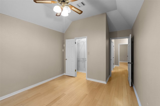 unfurnished bedroom featuring light hardwood / wood-style floors, vaulted ceiling, ceiling fan, a closet, and a spacious closet