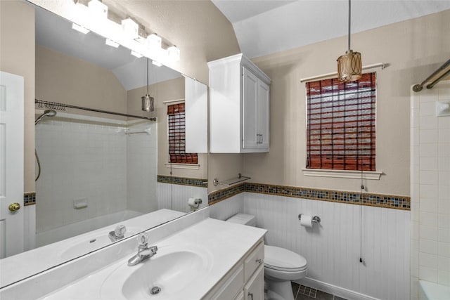 full bathroom with tile walls, vanity, vaulted ceiling, toilet, and tiled shower / bath