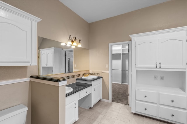 bathroom with vaulted ceiling, vanity, tile patterned floors, and toilet