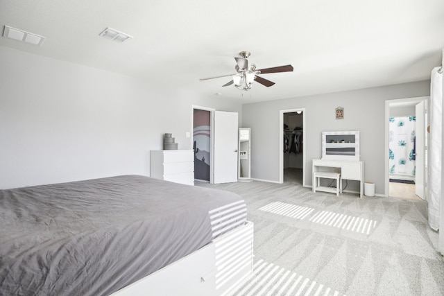 carpeted bedroom featuring ceiling fan, a walk in closet, ensuite bathroom, and a closet