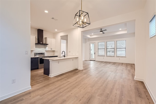 kitchen featuring white cabinets, a wealth of natural light, wall chimney exhaust hood, and stainless steel electric range oven