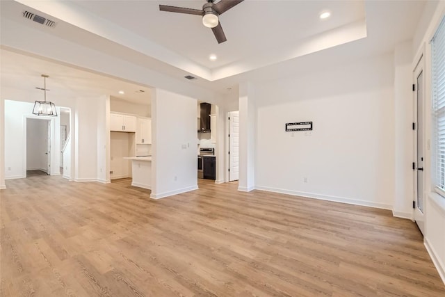 407 Meadowlark St, Austin, TX 78734 - unfurnished living room with a ceiling fan, light wood-style floors, recessed lighting, a tray ceiling, and a chandelier