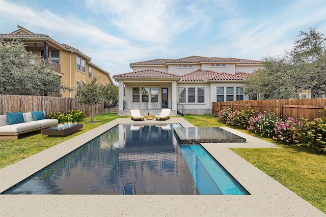 rear view of property featuring a fenced in pool, outdoor lounge area, and a yard