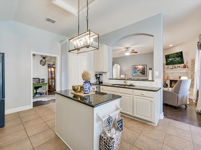 kitchen with ceiling fan with notable chandelier, pendant lighting, sink, light tile patterned floors, and white cabinetry